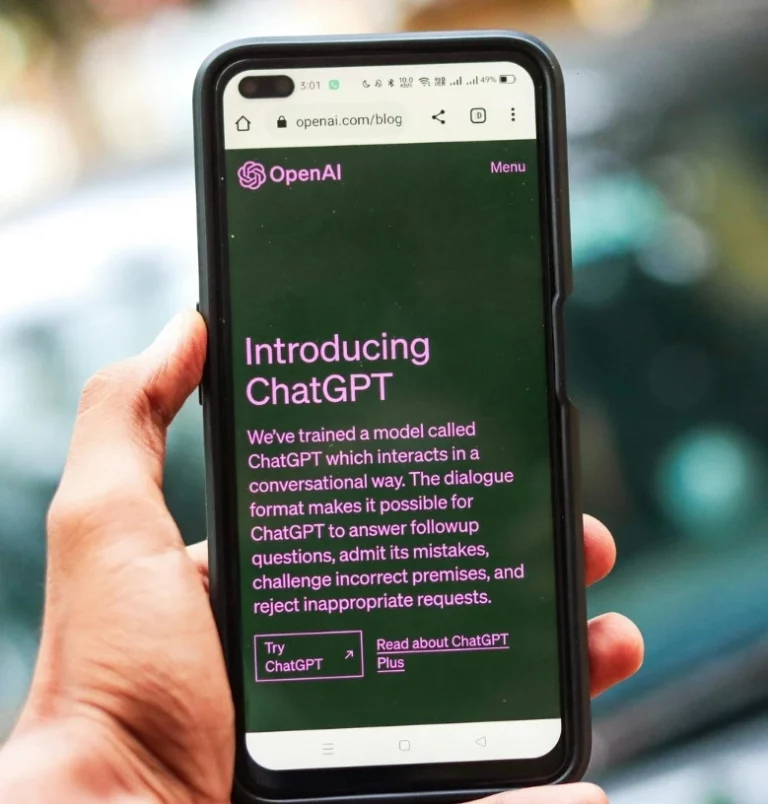 Person using a mobile phone with the OpenAI website open, presenting ChatGPT as a generative artificial intelligence tool for conversations.